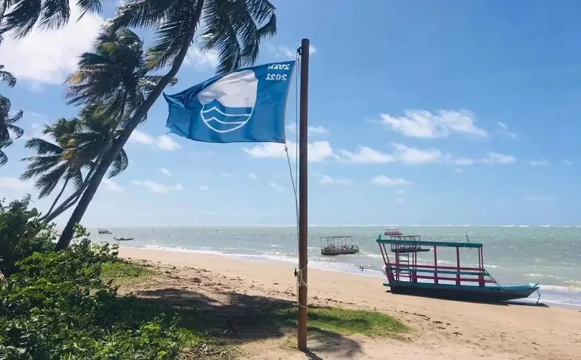 Blue Flag flying on a beach on the Alagoas coast, with coconut palms and a boat on the sand