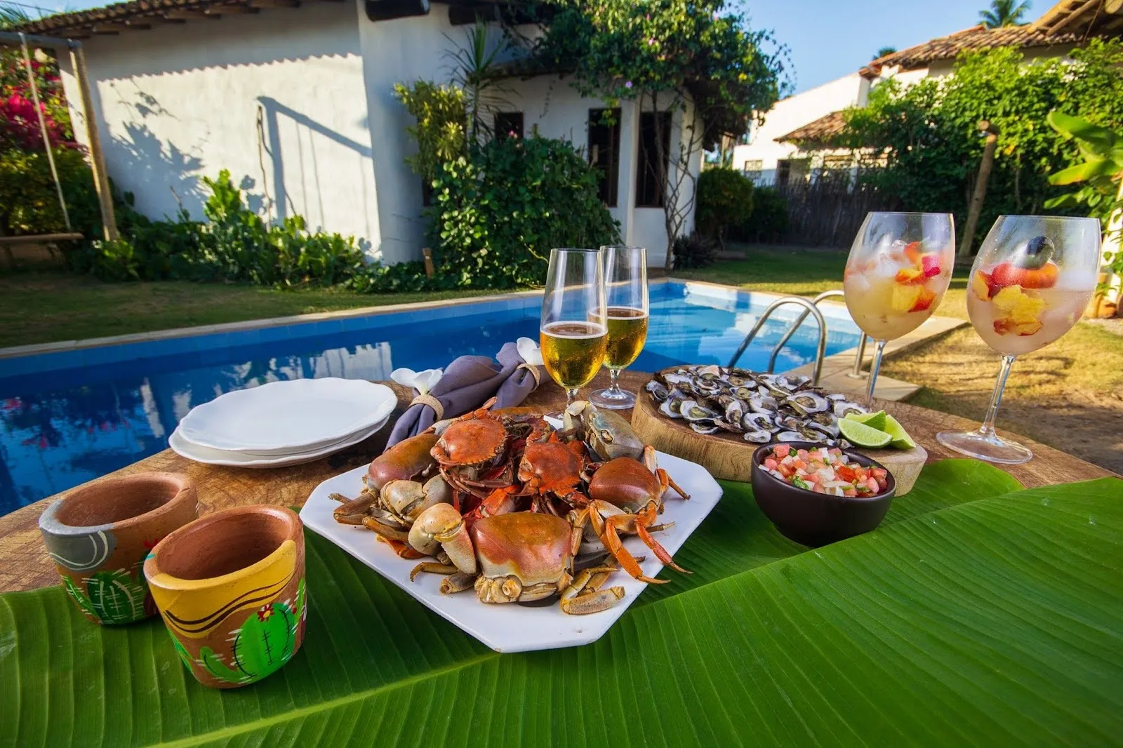 Mesa de petiscos e taças junto à piscina do Pontal da Enseada