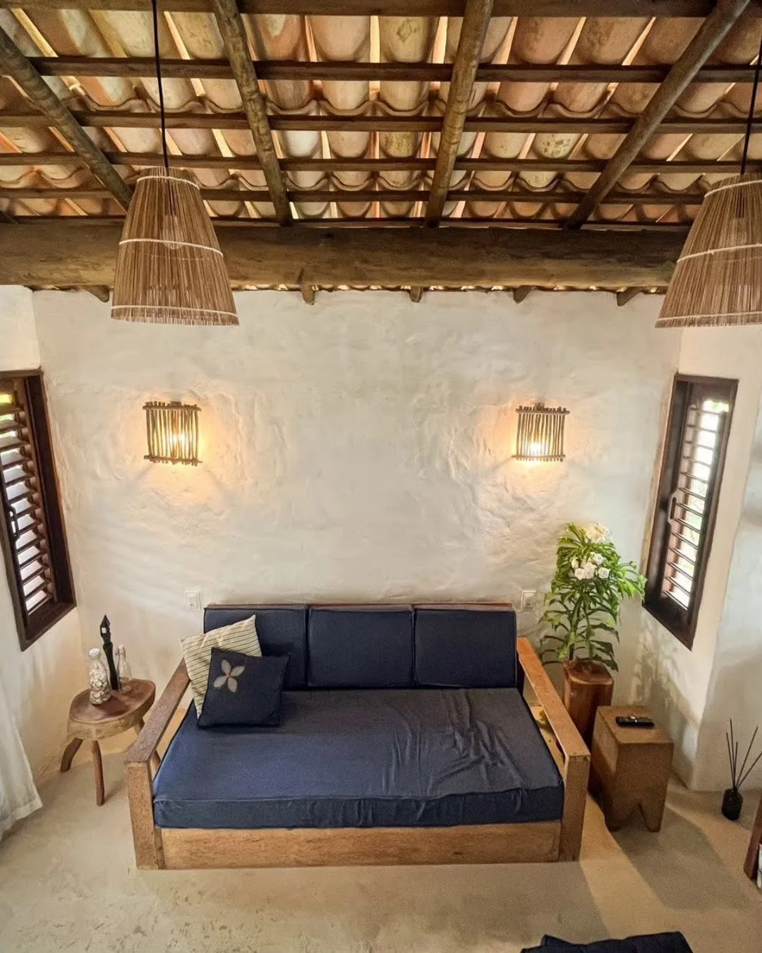 Sala de estar de uma das casas, com sofá-cama baixo e teto de madeira
