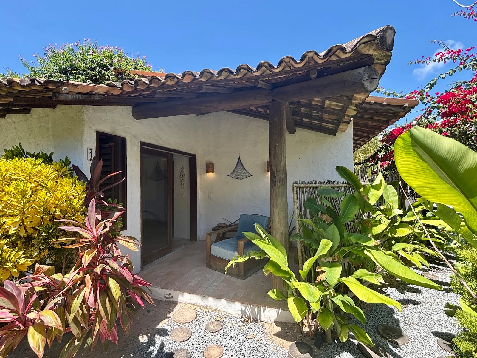 Entrada de uma das casas do Pontal da Enseada, cercada de jardim tropical