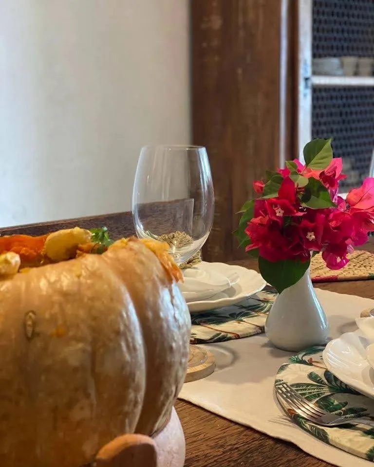 Mesa posta com abóbora decorativa e flores tropicais
